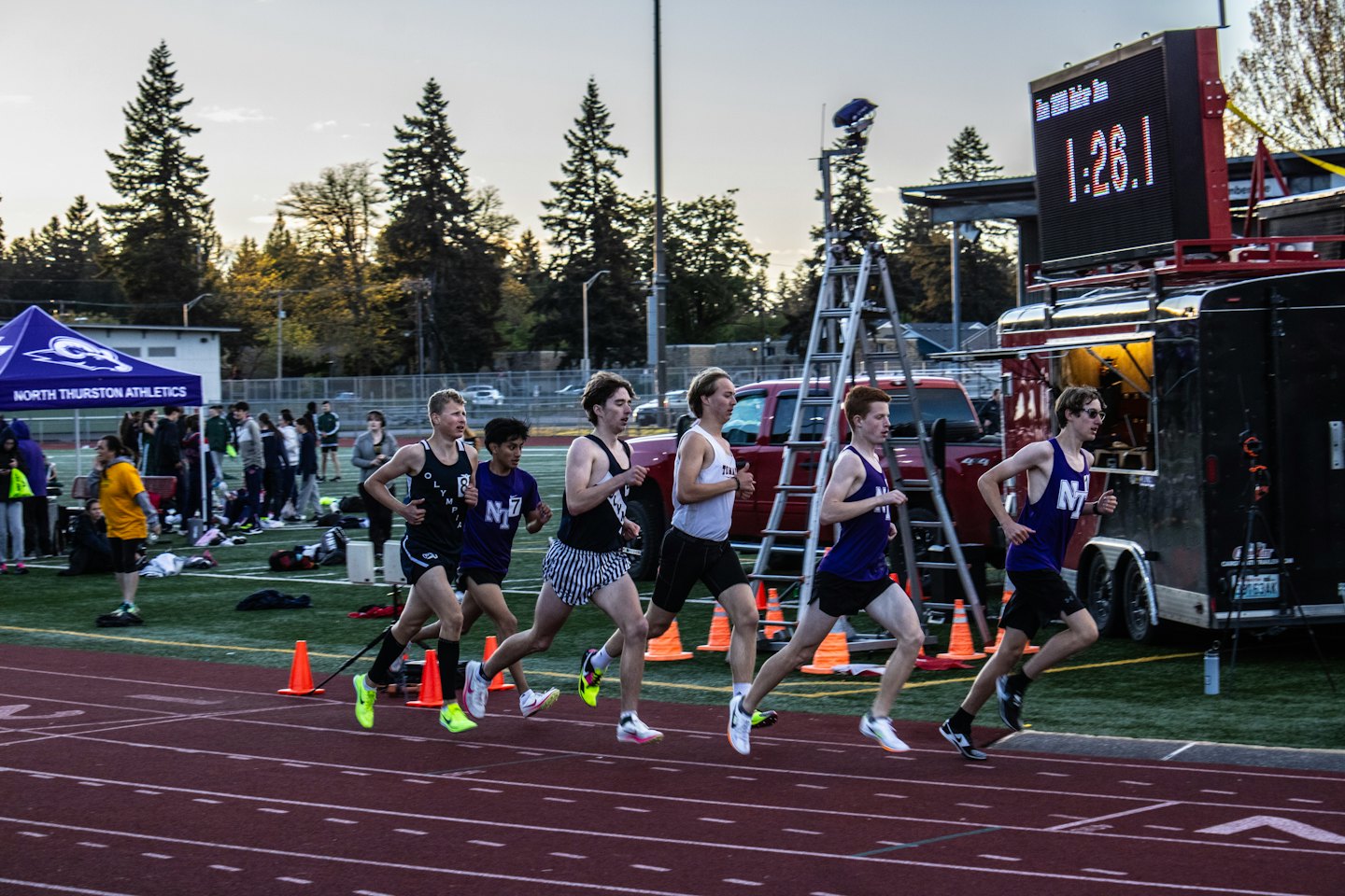Athletes run around a track during a competition.