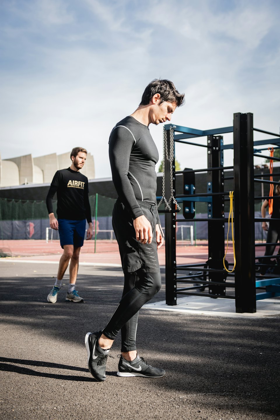 Two men stretching and exercising at an outdoor calisthenics park.