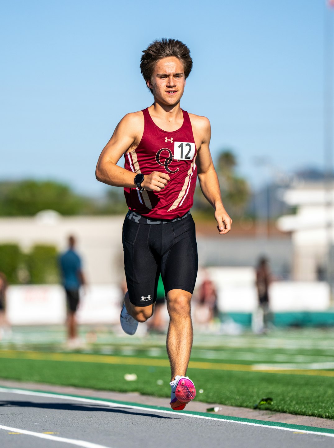 Runner wearing race bib twelve sprints on an outdoor track.